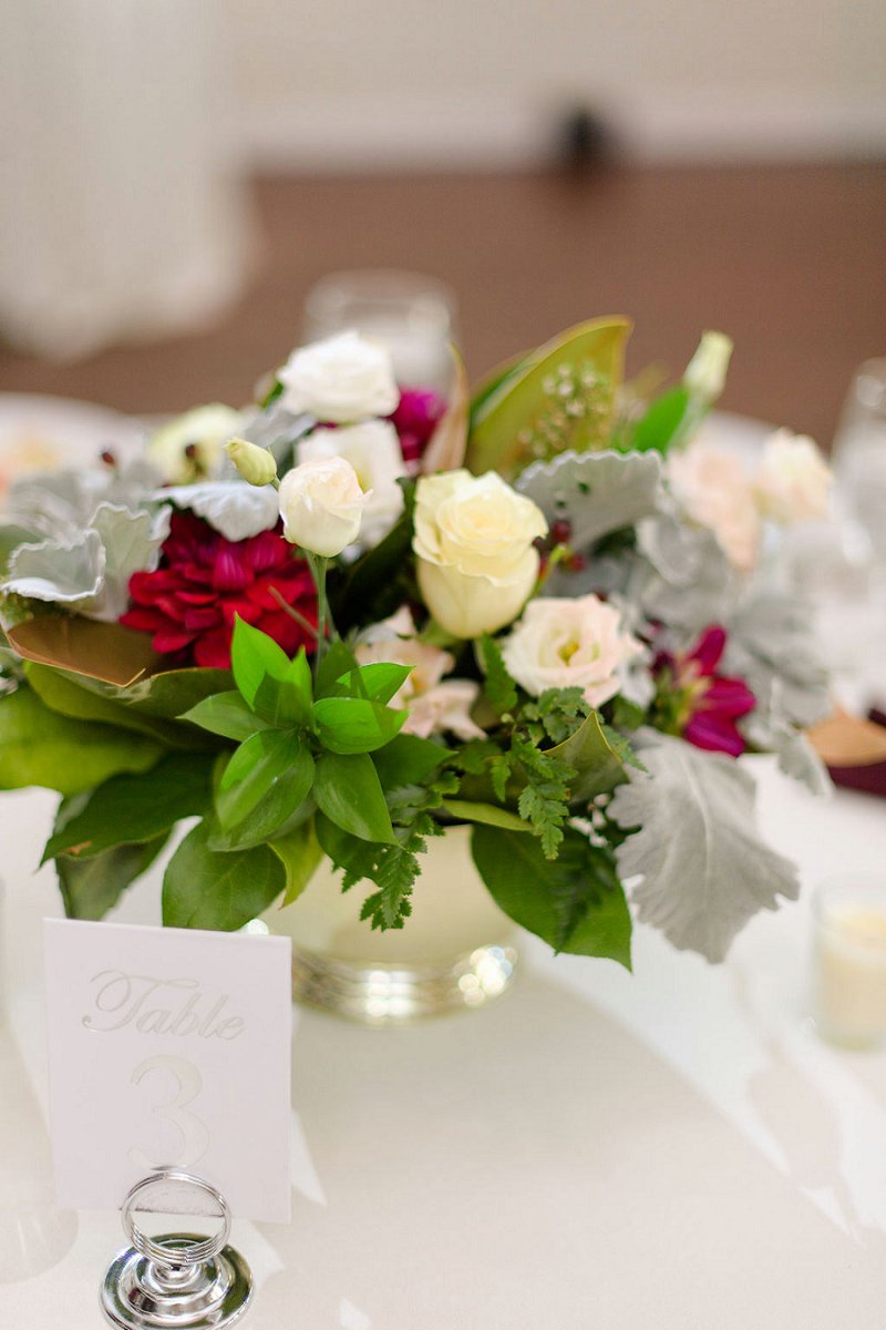 Simple low floral centerpiece with dusty miller and a silver table number for winter wedding idea