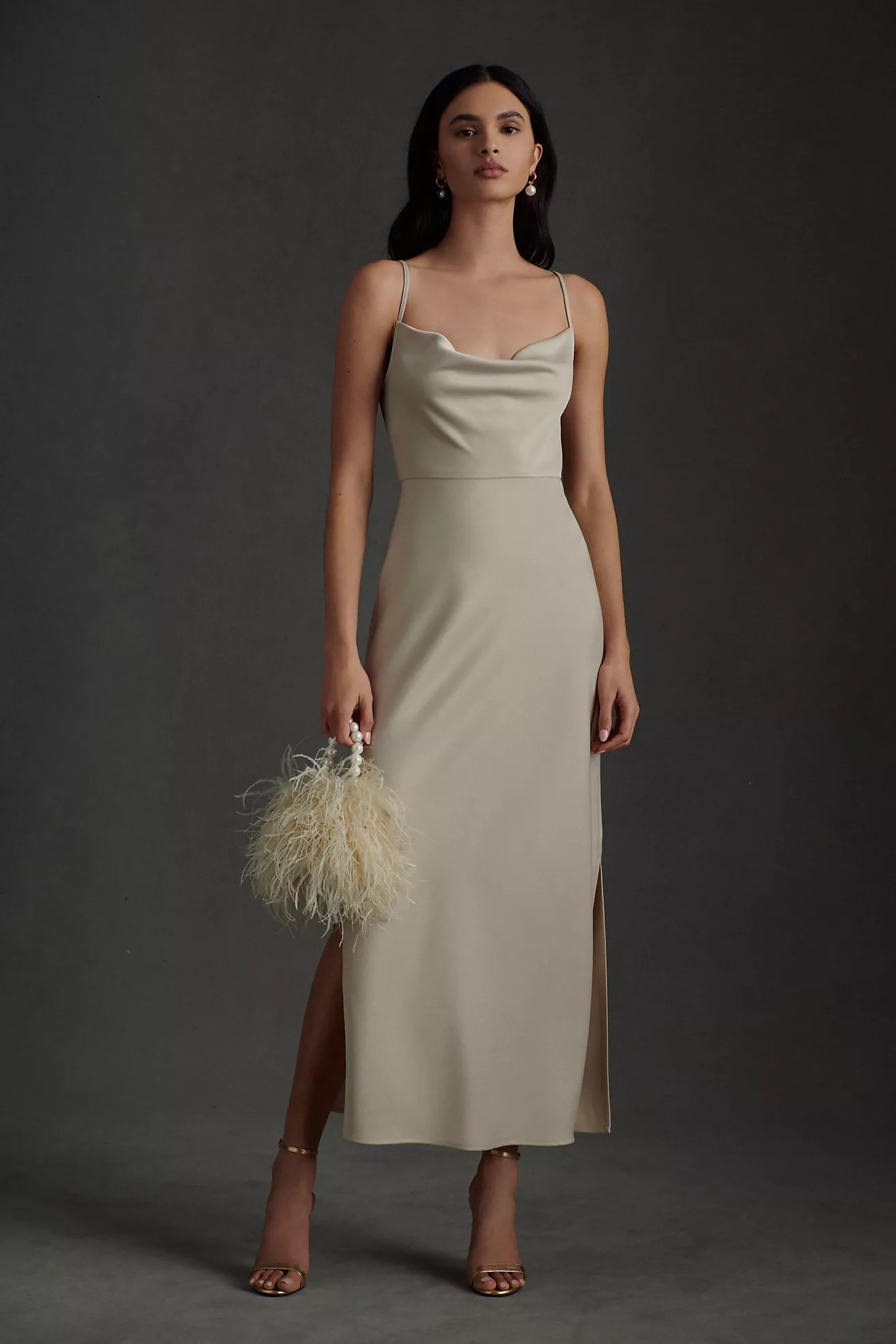 An elegantly draped cowl neckline completes the BHLDN Cali Satin Midi Dress. With a modern midi silhouette, the silky slip dress falls gracefully, ending with daring slits on either side a stunning choice for bridesmaids and wedding guests alike.