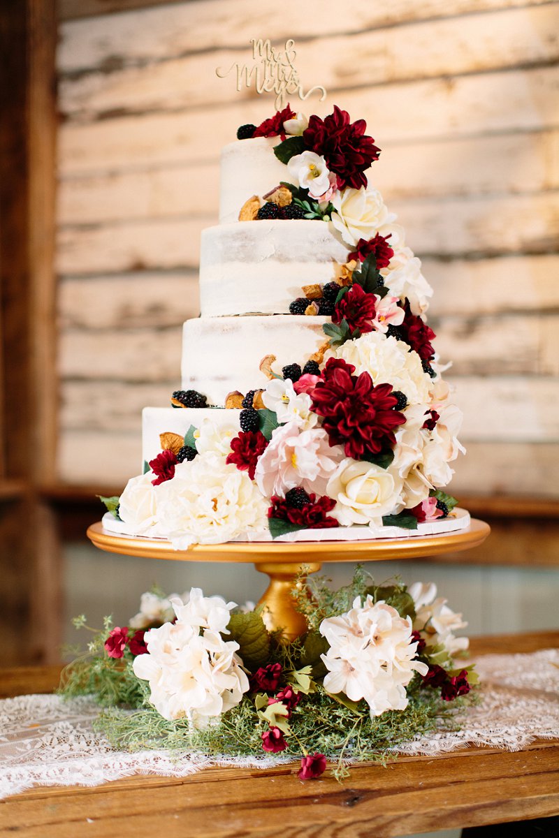 Rustic fall wedding cake on top of a wine barrel table with flowers