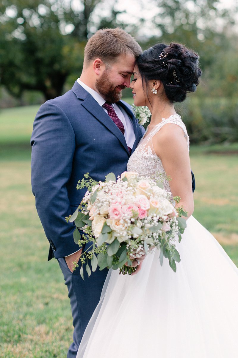 Rustic wedding style ideas with groom in navy blue suit and bride in a full tulle and lace sleeveless gown with illusion neckline