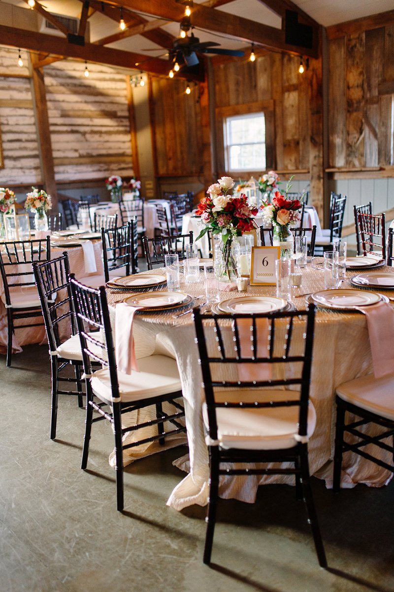 Rustic barn wedding reception with fall colored flower centerpieces and gold details