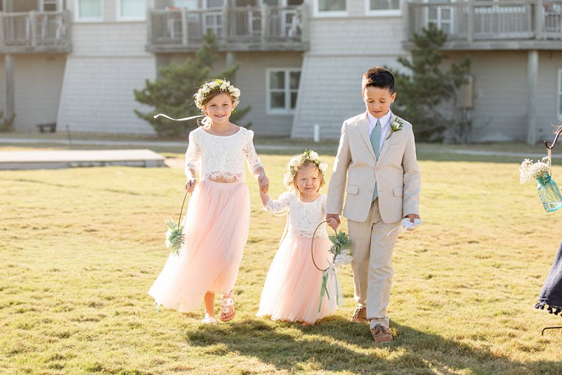 Adorable flower girls in lace tops and pink tulle skirts holding a ring shaped beach flower bouquet at Sanderling Resort in Outer Banks