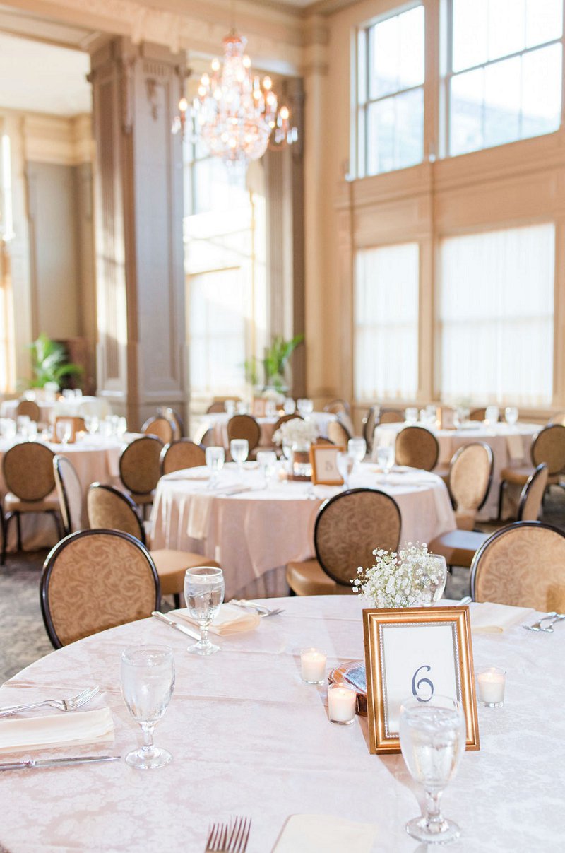 Classic ballroom wedding reception with babys breath centerpieces and gold frame table numbers