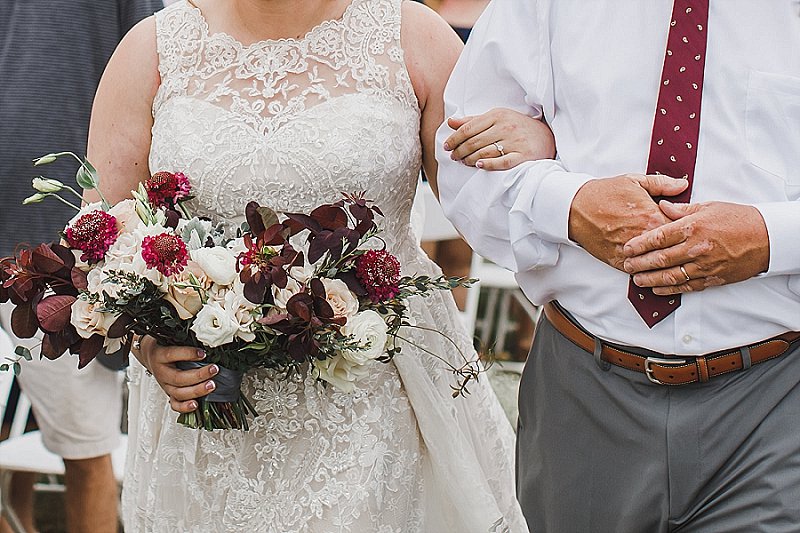 Bride walking down the aisle with her dad and lovely wedding bouquet at fall wedding