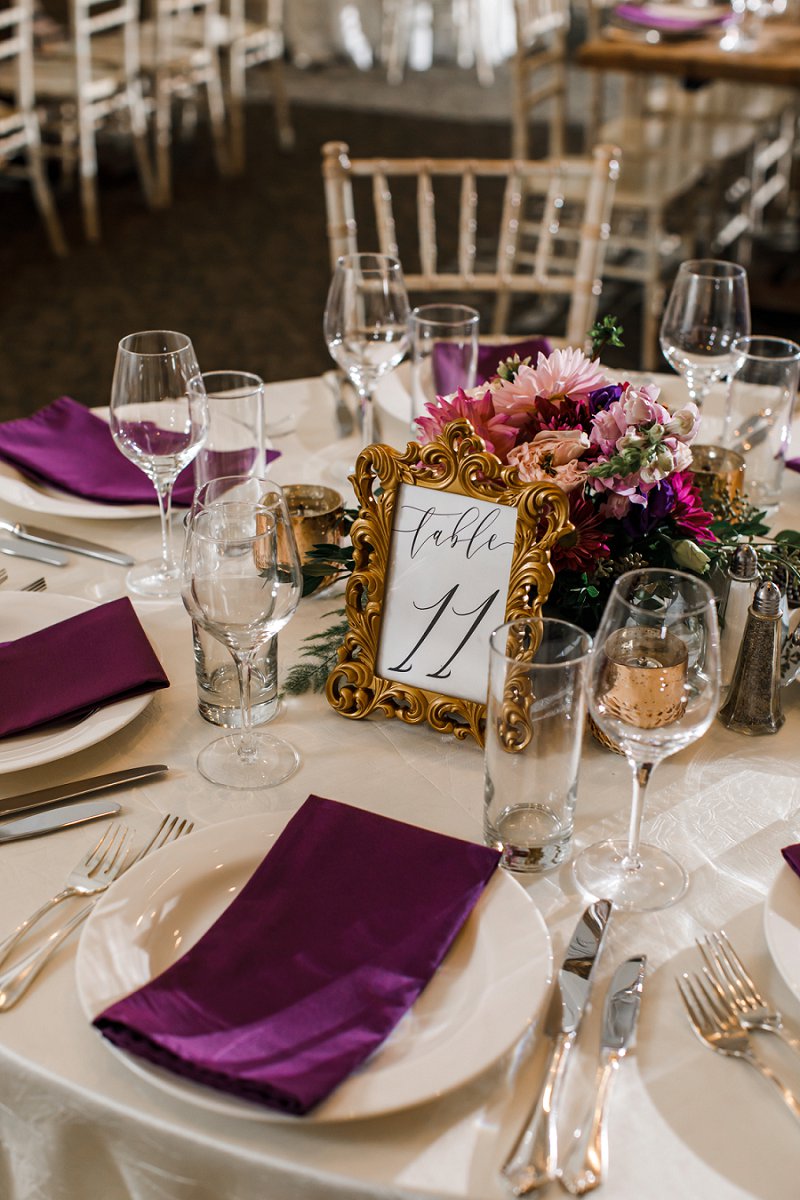 Vintage inspired wedding table number in elegant gold frame decorated with small jewel toned wedding centerpiece