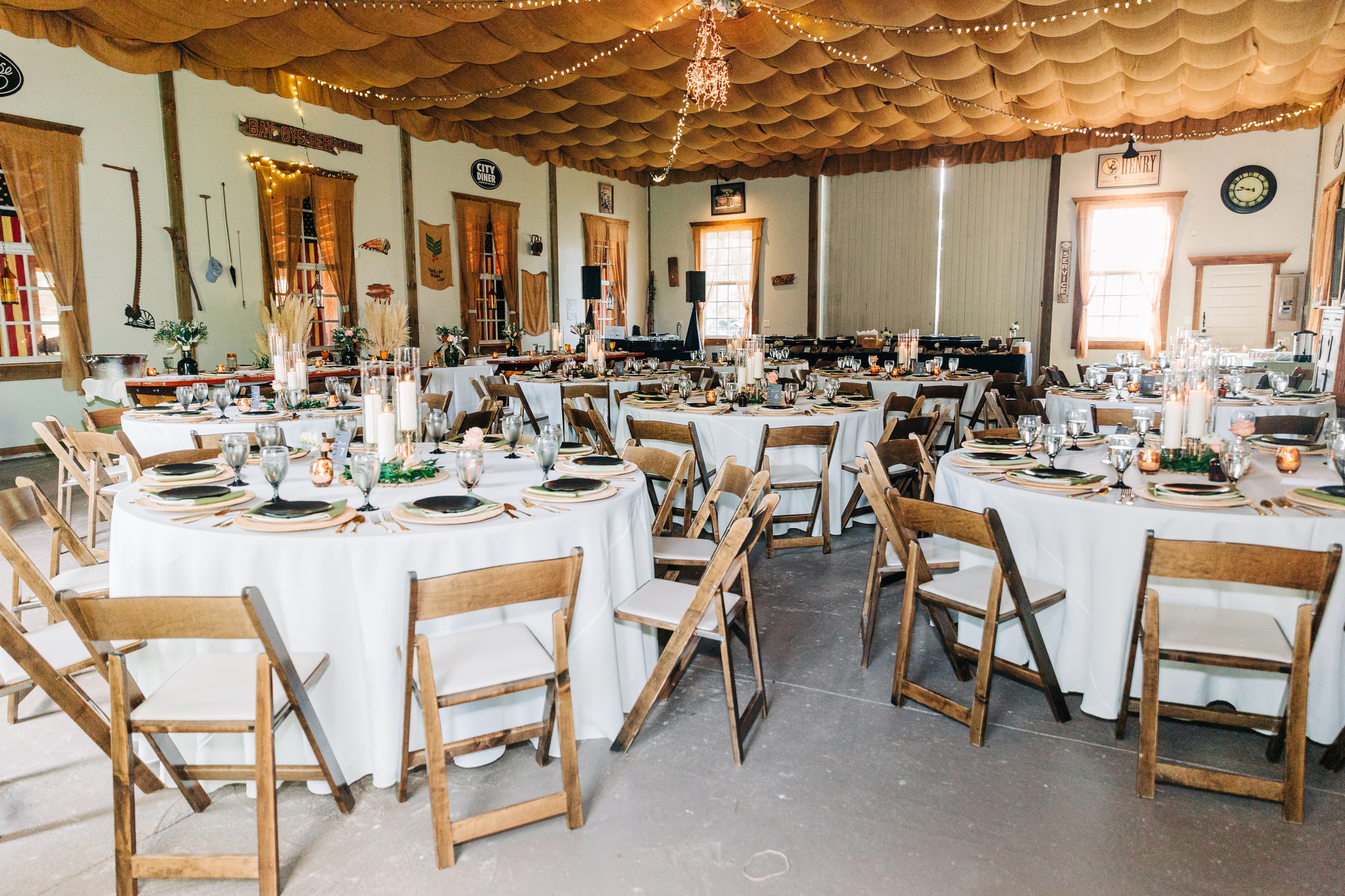 Rustic barn wedding reception with draped burlap ceiling and wooden folding chairs