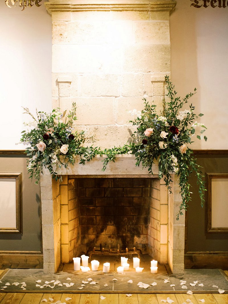 Beautiful wedding ceremony altar fireplace decor with two floral arrangements and candlelight